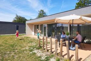 a family sitting at a table with an umbrella at RCN Vakantiepark de Schotsman Bungalow de Boei in Kamperland