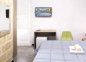 B&B La Dimora dei Professori في ليتشي: غرفة نوم مع سرير ومكتب مع كرسي أخضر
