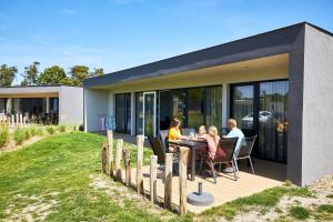 a family sitting at a table outside of a house at RCN Vakantiepark de Schotsman Bungalow de Bevelander in Kamperland
