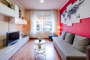 - un salon avec un canapé et un mur rouge dans l'établissement Three Bedroom Apartment in Sants, à Barcelone