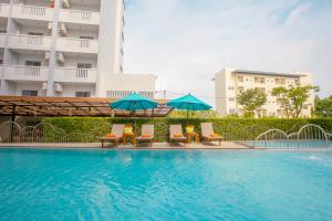 a swimming pool with chairs and umbrellas in front of a building at Recenta Phuket Suanluang in Phuket Town