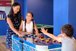 a woman and two children playing a game with a table at Paradise Bay Resort in Mellieħa