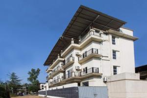 a tall white building with a black roof at Dean Villa in Lonavala