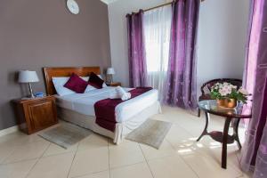 a bedroom with a bed with purple curtains and a table at Bilene Beach House in Vila Praia Do Bilene +29 photos