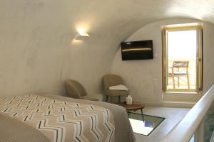 a bedroom with a bed and a tv and a window at Esperia Luxury Suites in Astypalaia