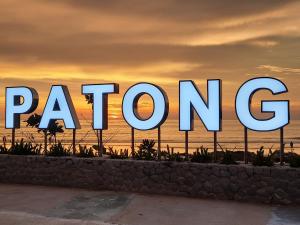 Una gran señal que lee lorón frente a una puesta de sol en Ocean Rock Kalim, en Patong Beach