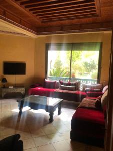 a living room with red couches and a large window at la palmeraie village Appartement in Marrakech