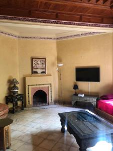 a living room with a fireplace and a tv at la palmeraie village Appartement in Marrakesh