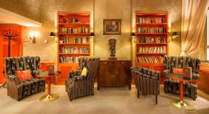 uma biblioteca com cadeiras e mesas e estantes de livros em Dvorak Spa & Wellness em Karlovy Vary