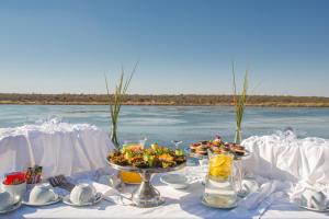 a table with two plates of food on the water at Little Mongena Tented Camp in Klipdrift