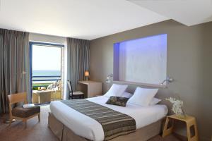 ダムガンにあるホテル ドゥ ラ プラージュの大きなベッドと大きな窓が備わるホテルルームです。