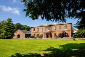 een groot bakstenen gebouw met een groen gazon bij The Greenhill Hotel in Wigton