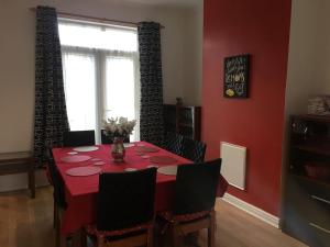 een eetkamer met een tafel met een rode muur bij 5 Bedroom House For Corporate Stays in Kettering in Kettering
