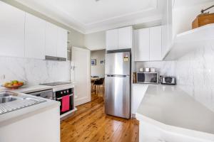 uma cozinha com armários brancos e um frigorífico de aço inoxidável em The Summit House em Katoomba