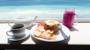 a breakfast plate of food and a cup of coffee at Phinisi Hostel Bira in Bira