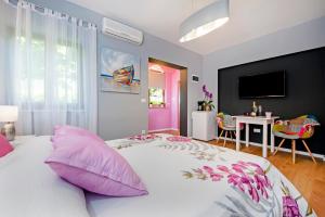 ein Schlafzimmer mit einem großen weißen Bett mit rosa Kissen in der Unterkunft Apartments Modrušan in Rovinj