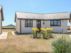 a small white house with yellow flowers in the yard at Sea Horses in Marazion