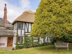 une maison au toit de chaume avec un banc devant elle dans l'établissement Fox Cottage, à Droitwich Spa