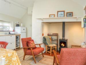 a living room with two chairs and a fireplace at Ffrwd Cottage in Bodorgan