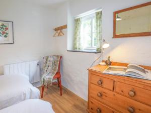 a bedroom with a wooden dresser with a bed and a window at Ffrwd Cottage in Bodorgan