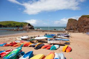 a bunch of kayaks and boats on a beach at Hope & Anchor in Hope Cove