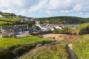a small town on a hill with a body of water at Hope & Anchor in Hope Cove