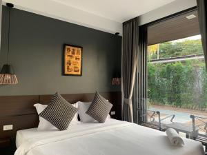 a bedroom with a bed and a large window at The CHESS Samui in Chaweng