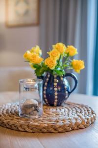 a blue vase with yellow roses and a glass at Ferienanlage Margaretenhof in Neujellingsdorf