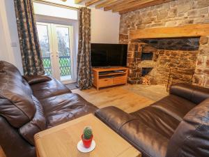 a living room with a leather couch and a fireplace at Crooked Hill Cottage in Ammanford