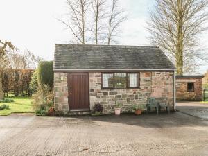 uma pequena casa de tijolos com uma porta vermelha e duas cadeiras em Cordwainer Cottage em Stoke-on-Trent