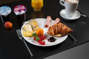 a plate of breakfast food on a table with a cup of coffee at BLOOM Boutique Hotel & Lounge Basel in Basel