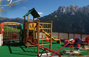 a playground with a play equipment and a mountain at Family & Wellness Hotel Fontana in Vigo di Fassa