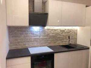 kuchnia z białymi szafkami i czarnym zlewem w obiekcie Apartament 100 Apartamenty No 1 Ogród w Centrum w Szczecinie