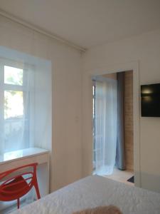 czerwone krzesło w białym pokoju z sypialnią w obiekcie Apartament 100 Apartamenty No 1 Ogród w Centrum w Szczecinie
