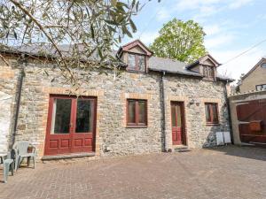 a stone house with red doors and a brick driveway at 2 Hwyrfryn Stables in Penmaen-mawr