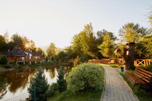 un parc avec une rivière et un banc à côté d'un lac dans l'établissement Ведмежа гора Family Resort & Spa, à Yaremtche