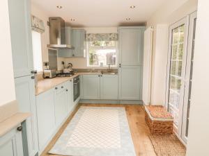 a kitchen with white cabinets and a white rug at Tan Y Goeden in Pwllheli