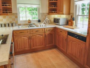 a kitchen with wooden cabinets and a sink at Charlton Lodge in Mawnan