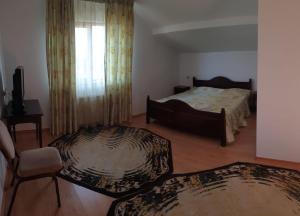 a bedroom with a bed and a chair and two rugs at Motel Balcost in Piatra Neamţ +21 photos