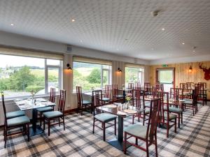 uma sala de jantar com mesas, cadeiras e janelas em Craigvrack Hotel & Restaurant em Pitlochry