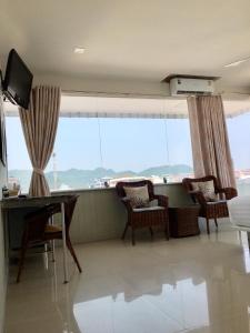 a living room with a table and chairs and a large window at PierView Rooms in Hua Hin