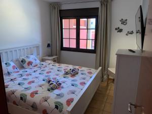 a bedroom with a bed with a colorful comforter and a window at Casa Achille in El Cotillo