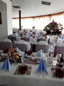 une salle à manger avec des tables et des chaises blanches avec des serviettes bleues dans l'établissement Motel Balcost, à Piatra Neamţ