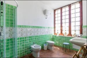 a green tiled bathroom with a toilet and a sink at Casa Sulky SantAntioco in Maladroscia +29 photos