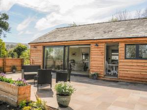 a wooden cottage with a patio with a table and chairs at Black Cat Bach in Abergavenny