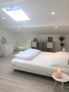 a bedroom with a large white bed with a skylight at Location Seignosse in Seignosse