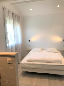 ein weißes Schlafzimmer mit einem Bett und einer Kommode in der Unterkunft Location Seignosse in Seignosse