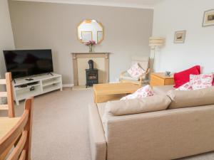 sala de estar con sofá y TV en The Wynd Apartment, en Morpeth