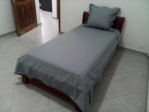 un letto con piumone blu e cuscino di St Chylifa a Toamasina