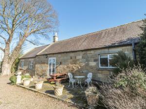 a stone cottage with a table and chairs in front of it at Holly Cottage in Alnwick